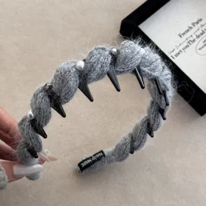 Détail d'un serre-tête tressé gris orné de pointes noires et de perles de style punk