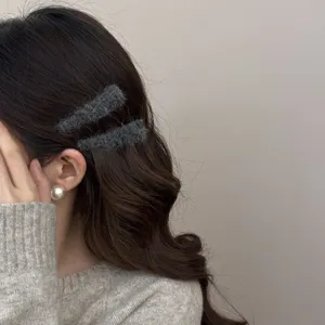 Close-up detail of soft grey wool rectangular BB hair clips styled on wavy brown hair