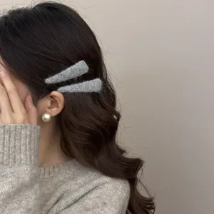 Close-up of gray wool felt horn hair clips worn on dark wavy hair for a cozy winter look