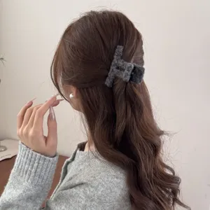 Nahaufnahme einer grauen Plüsch-Haarklammer, gestylt in langem welligem braunem Haar.