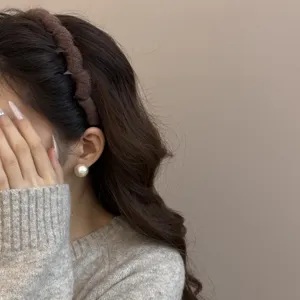 Detalle de una diadema de punto marrón ondulada para un estilo elegante de otoño.