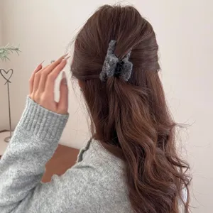 Eleganter dunkelgrauer Plüsch-Haarclip in Quadratform, getragen auf braunem welligem Haar