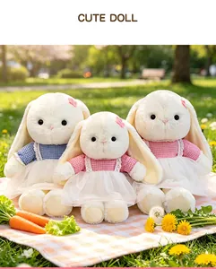 Three cute long-eared white bunny plushies wearing gingham dresses in a sunny park.