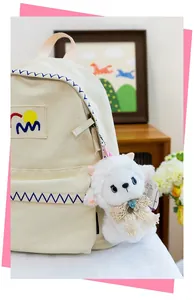 Close-up of cute plush sheep charm attached to a cream canvas backpack
