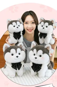 Close-up of cute husky plush toys with black bow ties held by a smiling model