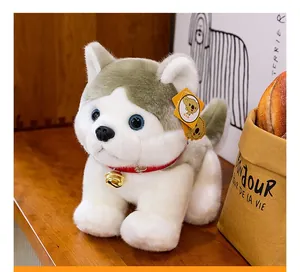 Primer plano del lindo peluche de husky con un collar rojo y un cascabel dorado.