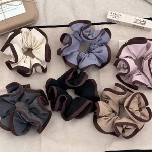 Detail view of multiple elegant hair scrunchies with wood ear edges in soft colors.