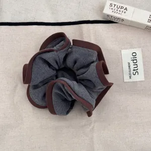 Detailed macro shot of a Korean style grey scrunchie with elegant brown ruffled edges