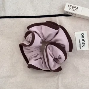 Detailed view of a mauve fabric scrunchie featuring elegant dark brown wood ear ruffled edges