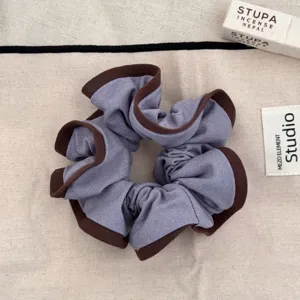 Close-up of grey-purple scrunchie with contrasting brown ruffled edges and texture