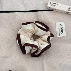 Close-up detail of elegant Korean style cream scrunchie with dark brown wood ear edges