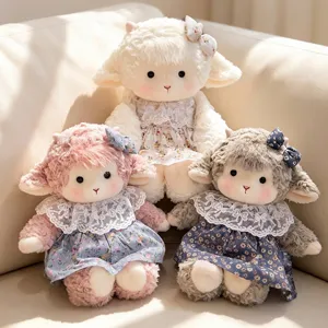 Close-up of three cute plush sheep dolls in floral dresses sitting on a beige sofa