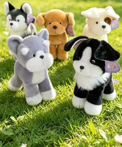 Collection of realistic plush puppy toys displayed on green grass in natural sunlight