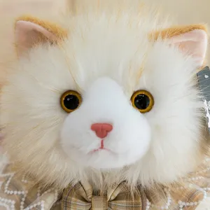Close-up detail of a plush cat toy with realistic fur, golden eyes and lace collar.