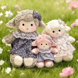 Set of three cute sheep plush dolls in grey, pink, and white floral dresses on grass.