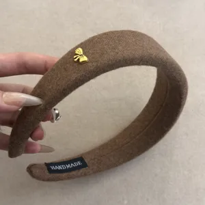 Primer plano de una diadema de lana marrón con un pequeño lazo dorado decorativo
