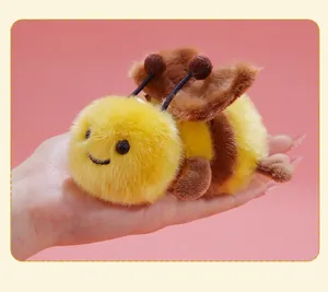 Detailed close-up of a cute, fluffy yellow and brown plush bee toy being held in a hand