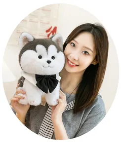 Detailed view of a cute husky plush toy dog with a black bow tie, held by a person.