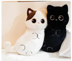 Cute white and black cat plush pillows leaning against a soft white bedroom pillow