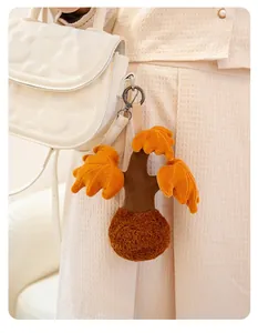 Close-up of a cute orange and brown plush insect keychain hanging on a white textured handbag