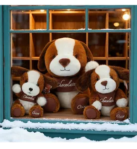 Drei Maillard-Hunde-Plüschtiere mit Stickereien in einem verschneiten Fenster im Nahbereich.
