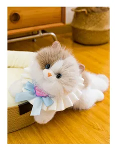 Nahaufnahme einer weichen dreifarbigen Plüschkatze mit blauer Schleife und weißem Kragen.