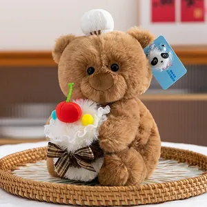 Simpatico orsetto di peluche marrone con cupcake, ciliegia e un piccolo cappello da chef