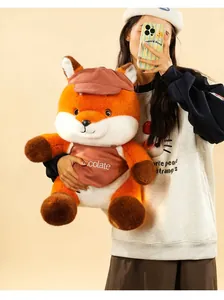 Close-up of cute plush fox toy with hat and chocolate apron held by a model