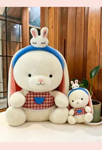 Vista dettagliata di due peluche di coniglio bianco a orecchie lunghe con fasce e grembiuli a scacchi