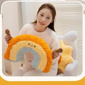 Detail view of a cute plush rainbow pillow being held, showing soft faux fur texture.
