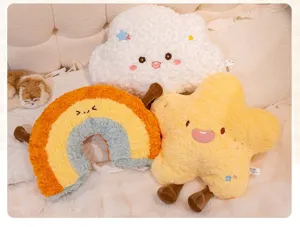 Group of cute plush star, cloud, and rainbow pillows with dangling legs on a bed.