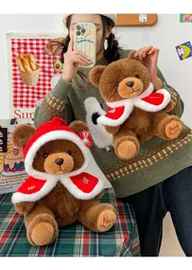 Close-up of a brown Christmas teddy bear plush wearing a festive red cape with fur trim