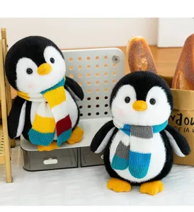 Detailed shot of two cute penguin plush toys wearing colorful knitted scarves on a desk.