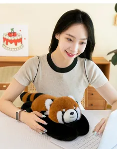 Peluche de petit panda réaliste en position allongée utilisée comme coussin de confort