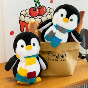 Cute cartoon penguin plush toy with colorful knitted scarf on wooden table