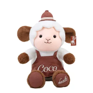 Simpatica bambola di agnello di peluche bianca e marrone con grembiule ricamato 'Coco'.