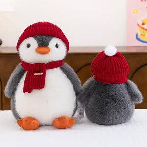 Adorable peluche de pingüino gris y blanco con gorro de punto rojo y bufanda a juego