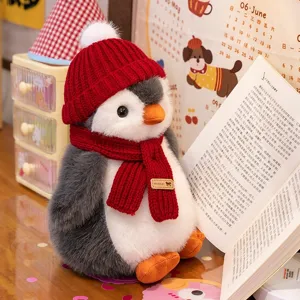 Adorable peluche de pingüino con gorro y bufanda de punto rojo en un ambiente acogedor