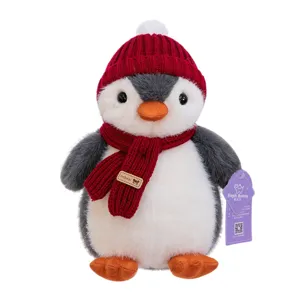 Adorable pingüino de peluche con gorro y bufanda de punto rojos sobre fondo blanco