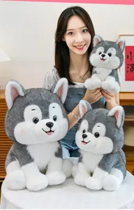 Three different sizes of husky dog plush toys held by a model in a cozy room