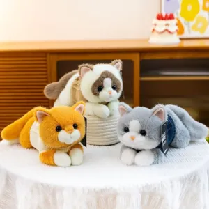 Primer plano de tres lindos gatitos de peluche con suéteres de punto sobre un mantel blanco