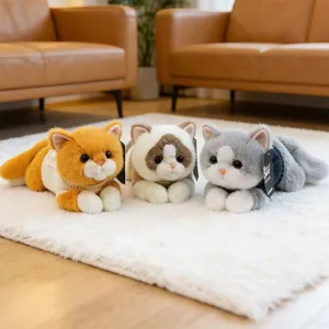 Tres gatos de peluche realistas de diferentes colores con jerseys en una alfombra.