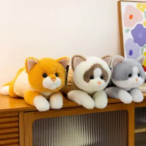 Tres gatos de peluche realistas con suéteres de punto en un estante
