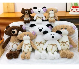 A group of cute plush animal dolls wearing bear-patterned pajamas on a white textured sofa