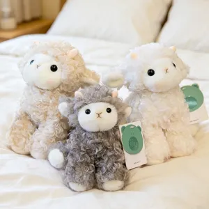 Three soft curly sheep plush toys in white beige and grey colors on a cozy white bed