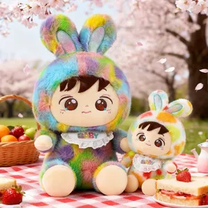 Süße Regenbogen-Hase-Plüschpuppe mit Lätzchen in einer schönen Picknick-Kulisse im Freien