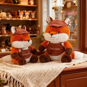 Two adorable orange fox plush toys wearing brown hats and aprons in a cozy toy shop setting