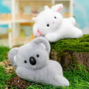 Adorable koala and white lamb plush toys lying on green moss in a natural garden