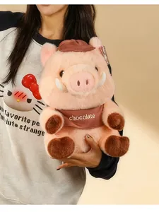 Close-up of a cute Maillard pig plush toy with "chocolate" embroidery being held.