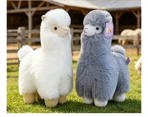 Close-up of white and grey plush alpaca toys with soft fur texture in farm setting.